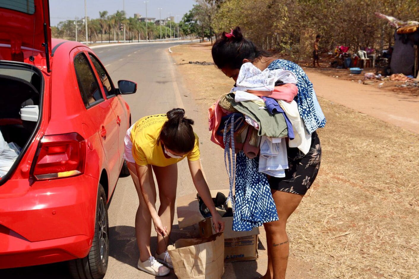 Pessoas organizando doações de roupas em um carro